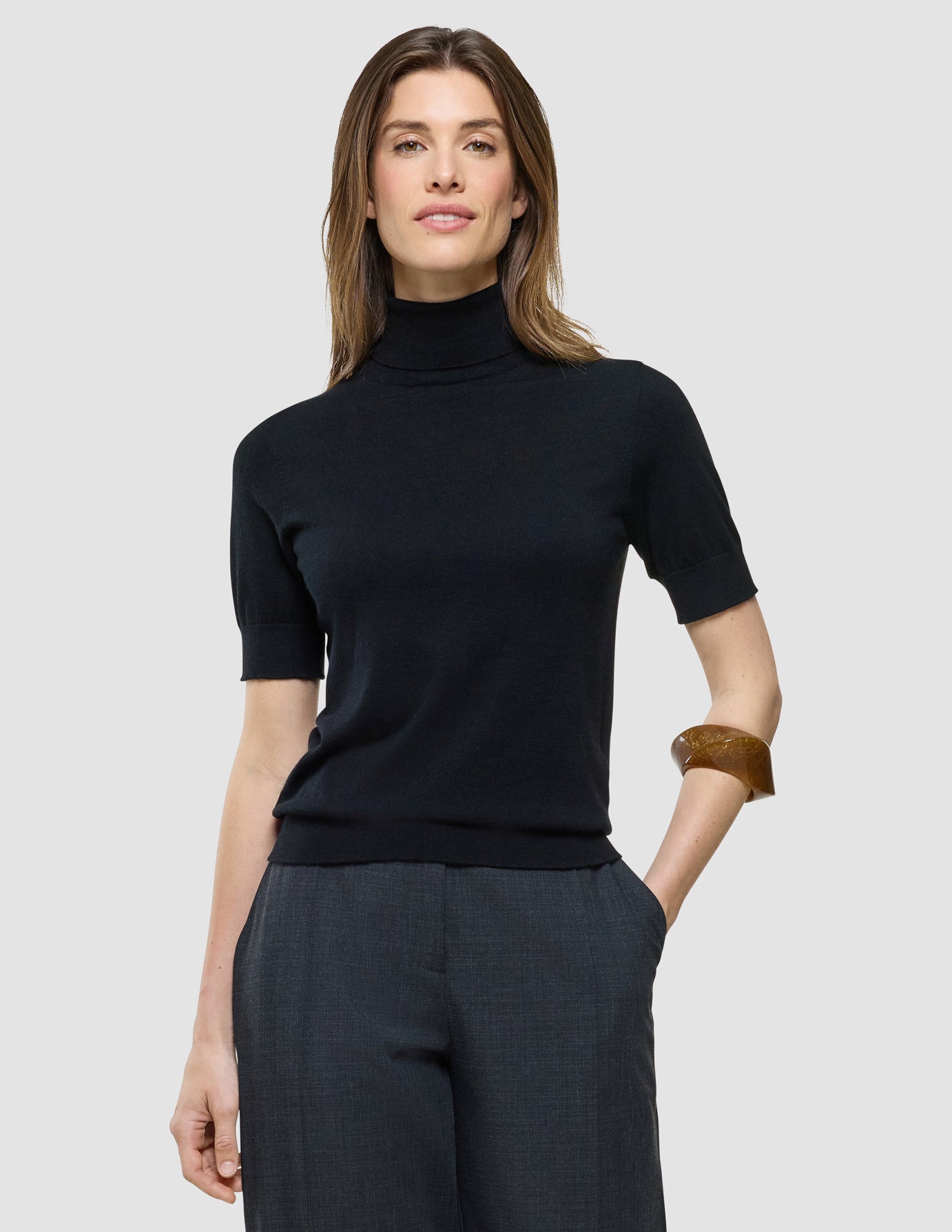 Quinn Turtleneck Short Sleeved i Black, halvfigur af kvinde iført sorte turtleneck og gråt buksehalvbukser.